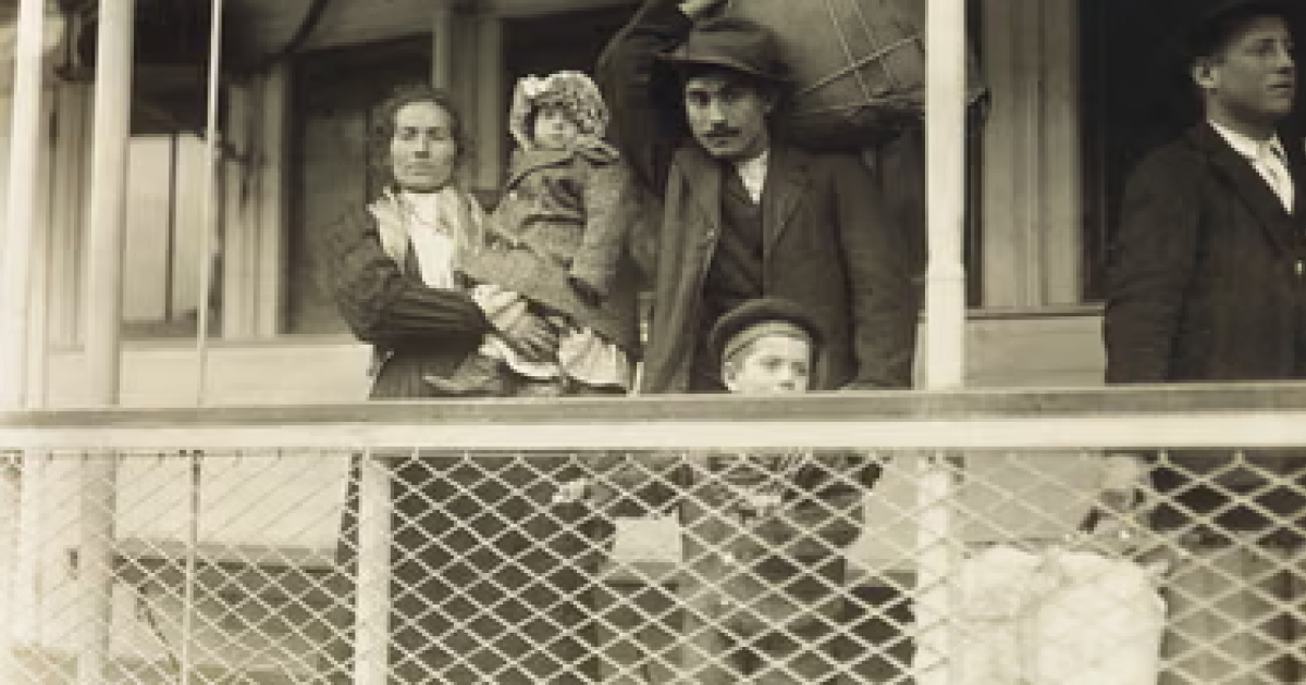Lewis Hine photograph of immigrants arriving at Ellis Island, circa 1905, with women and children in the registry room.